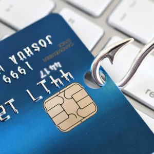 Phishing scam fraud identity theft - credit card on fishing hook on white computer keyboard